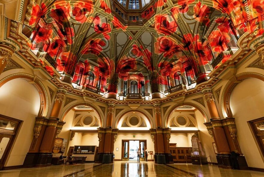 The grand, ornate domed interior of 333 Collins Street building, with a red poppy projection on the ceiling.