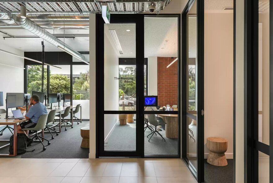 A modern glass-paneled entry door and open-plan workspaces ina co-working area in a building apartment complex.