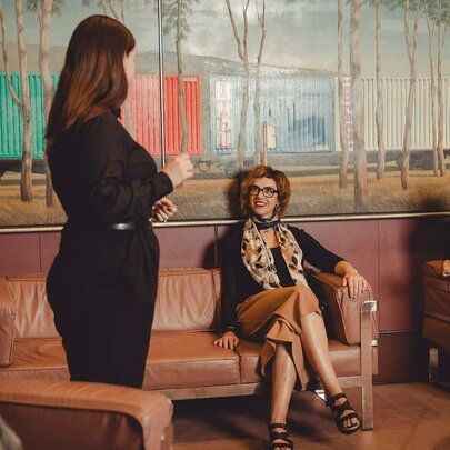 Four people on a tour of Arts Centre Melbourne, seated in a foyer, with a large mural behind them.