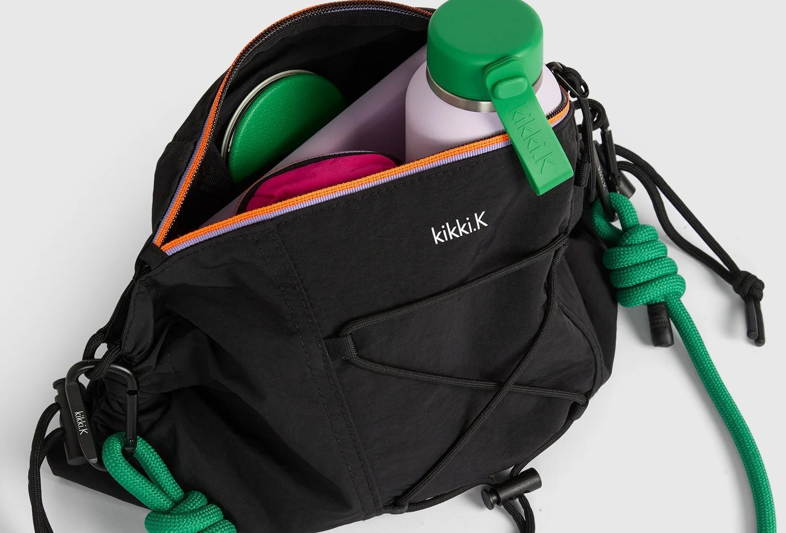 A black bag with a green strap with a water bottle and note book inside