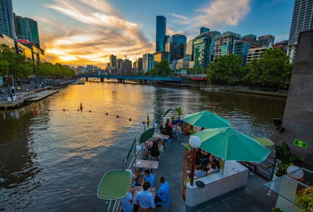 Sun setting down over the Yarra River with people sitting at a bar.