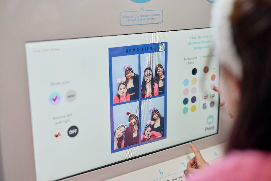 A woman is choosing photos in a photo booth