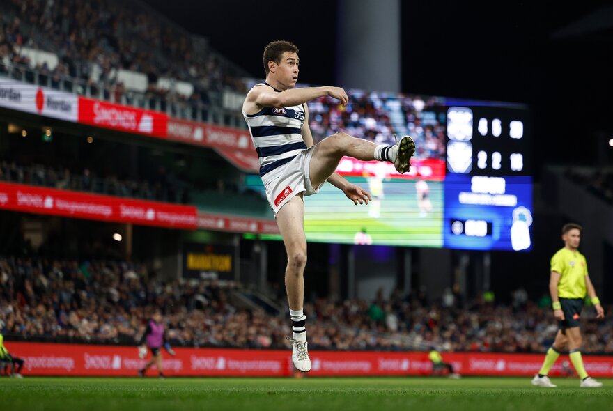 Geelong AFL football player kicking a ball during a match.