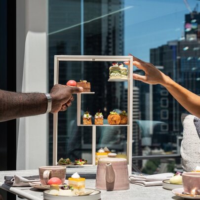 Hands clinking glasses over a display of food with views.