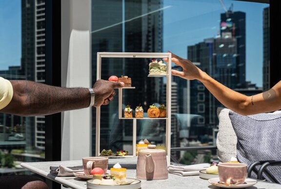Hands clinking glasses over a display of food with views.