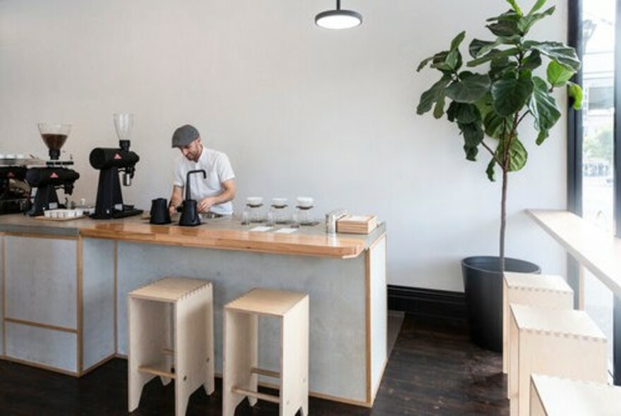 Barrister using a machine to make coffee in a cafe.