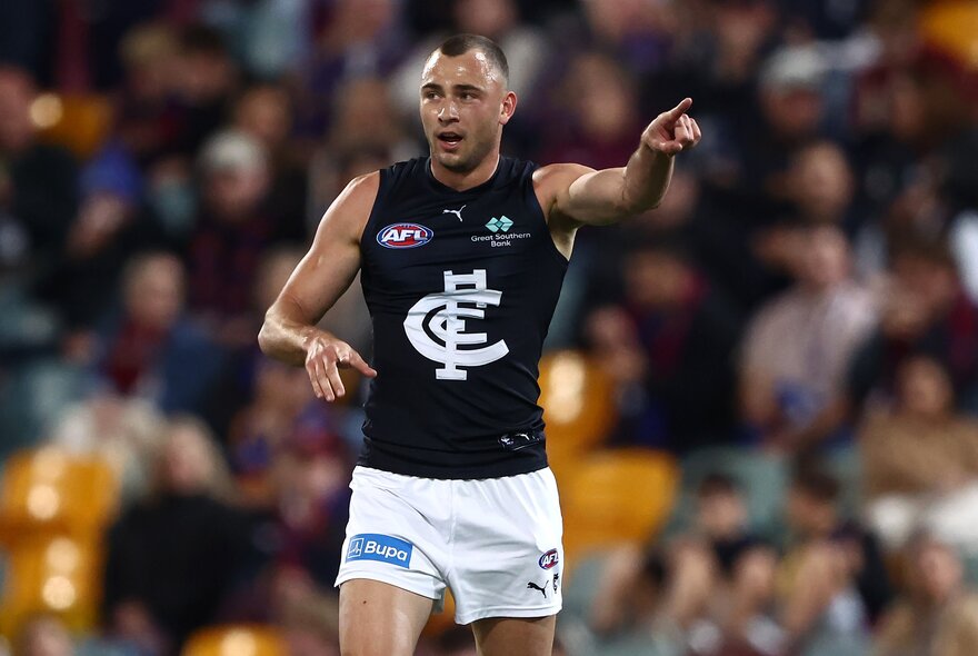 A Carlton AFL football player with his arm pointing during a match.