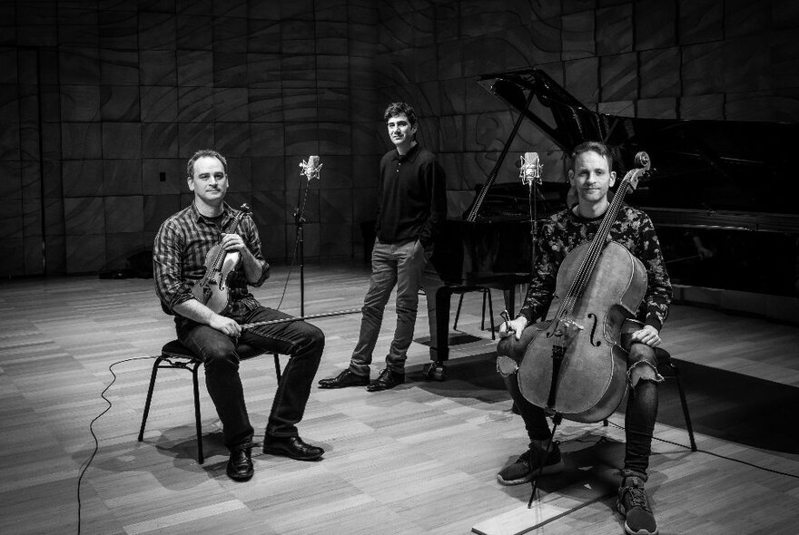 Benaud Trio, three men with instruments, seated violinist and cellist, standing pianist.