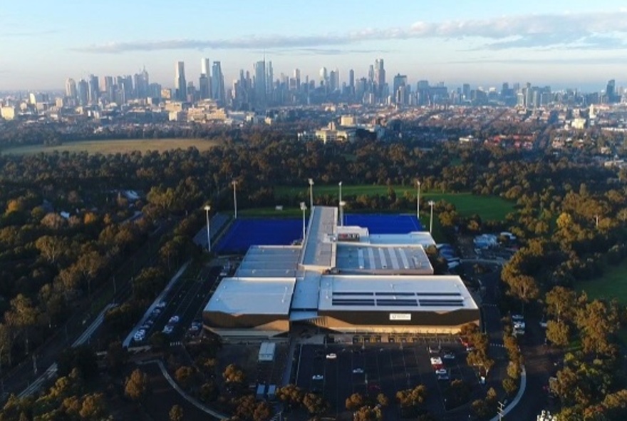 An aerial view of the Princes Park sporting precinct, with Melbourne's city skyline in the distance.
