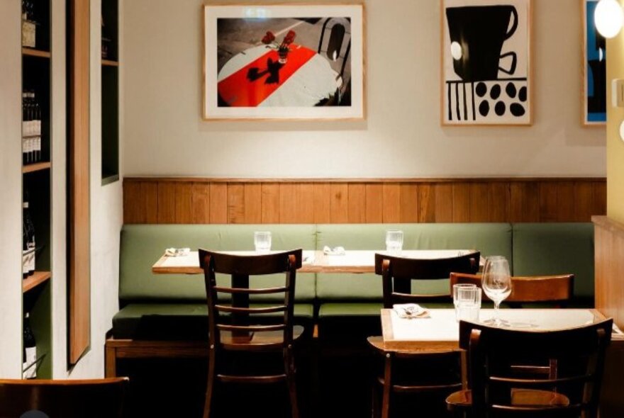 Restaurant interior of Hardware Club with artwork on the pale walls, banquette seating and tables and chairs in an inviting space.