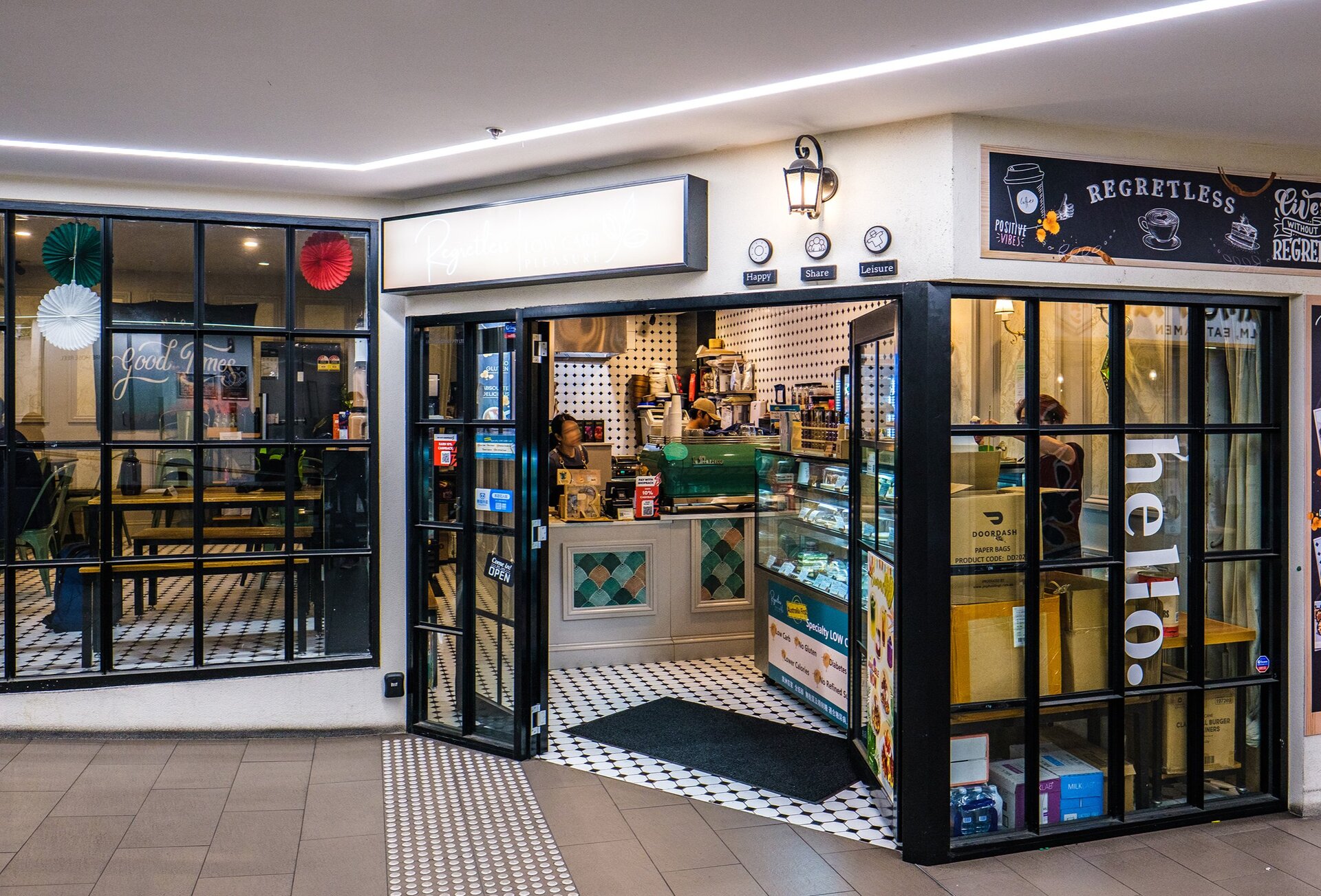 The exterior of a cafe inside a shopping arcade. There is a sign saying regretless. 