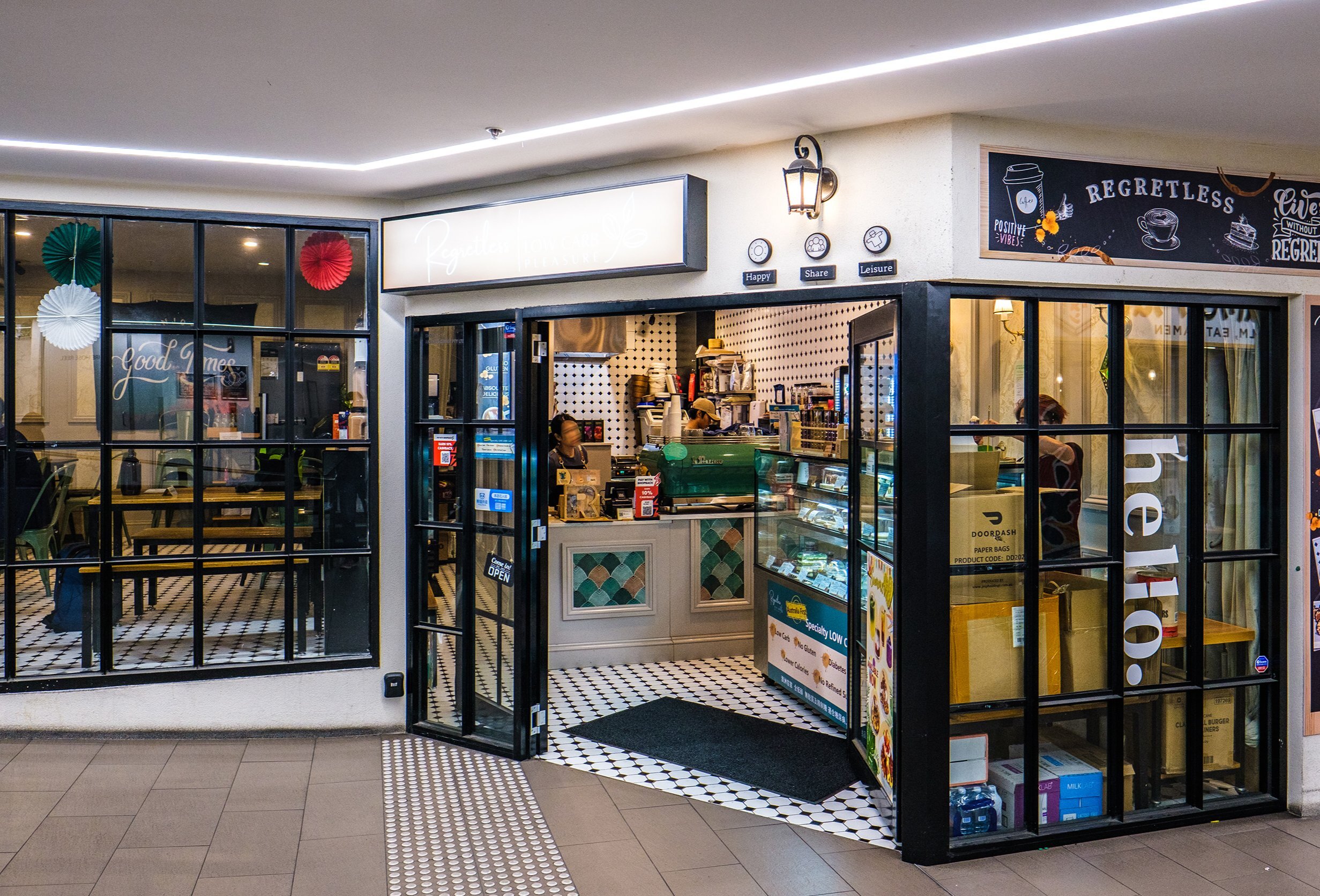 The exterior of a cafe inside a shopping arcade. There is a sign saying regretless. 