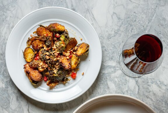 A plate of food next to a glass of red wine.