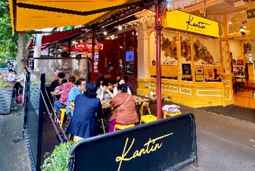 Yellow exterior of Kantin restaurant on Lygon Street with people seated at outdoor tables.