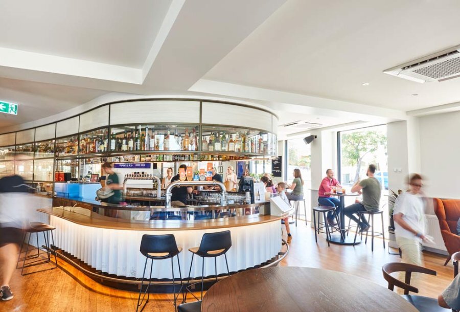 A busy pub with a curved bar and patrons at tables 