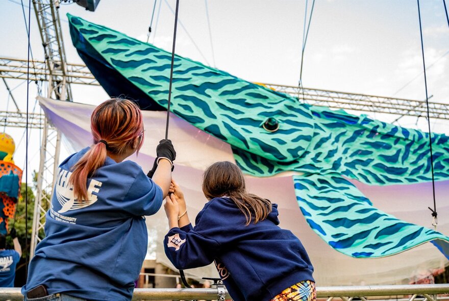 Children playing with a large outdoor whale sculptural installation.