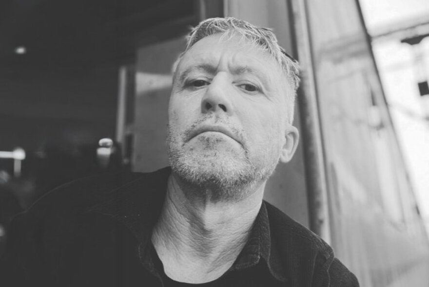 Black and white portrait of sports journalist and cricket commentator, Peter Lalor, looking down at the camera.