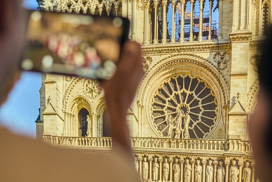 A person holding a tablet device up to a large print of the Notre-Dame de Paris.