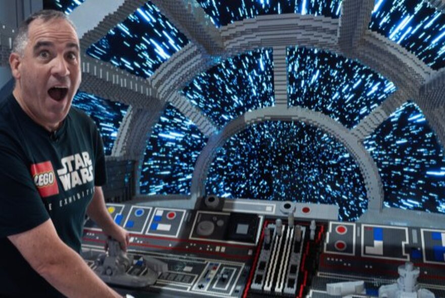 Master builder Ryan McNaught smiling in front of one his LEGO Star Wars creations at Melbourne Museum.