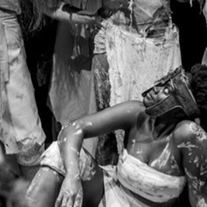Performers with painted bodies and stylised white clothing; black and white image.