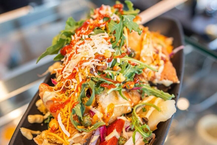 A shared dish of Indian food, with rocket leaves as garnish.