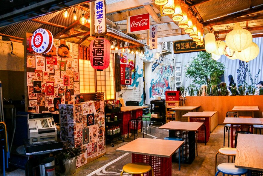 Japanese-style cafe interior with overhead lanterns, wooden tables and wall panels.