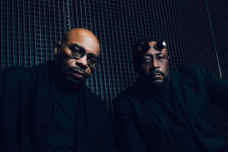 Two members of Octave One, a Detroit techno music group, both wearing black clothing and looking directly at the camera.