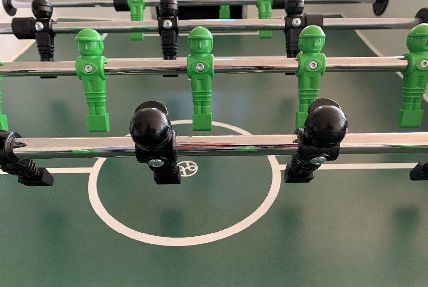 Green and black foosball characters on a bar.