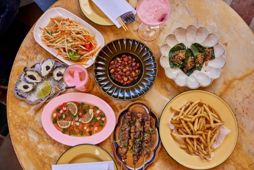 Looking down on a table with multiple dishes of food presented on various, non-matching platters. 