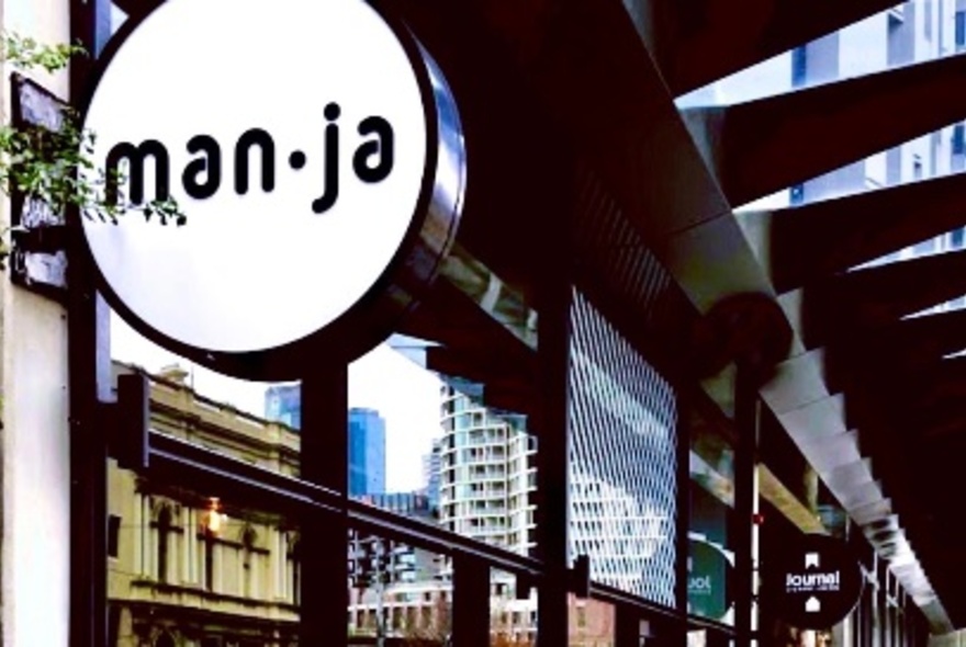 Cafe signage under walkway roof with buildings reflected in the windows.