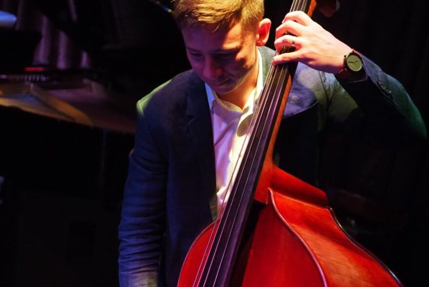 A musician playing a double bass, on stage.