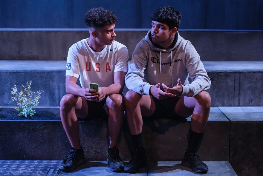 Two young people seated on stone steps.