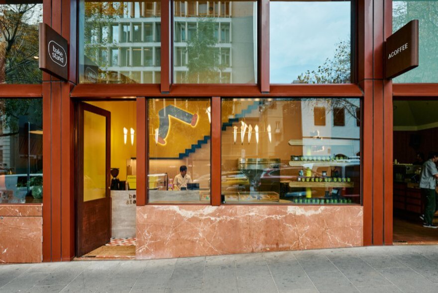 The external glass facade of BakeStand with rust-coloured columns.
