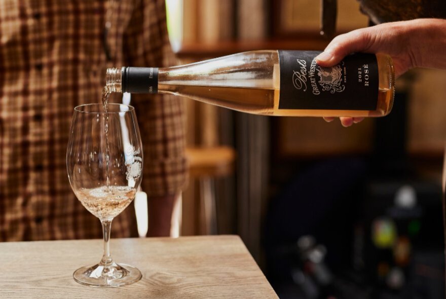A hand pouring wine from a bottle into a glass