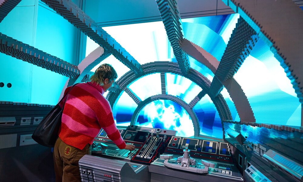 A Star Wars scene made of LEGO with someone at the controls of a spaceship.