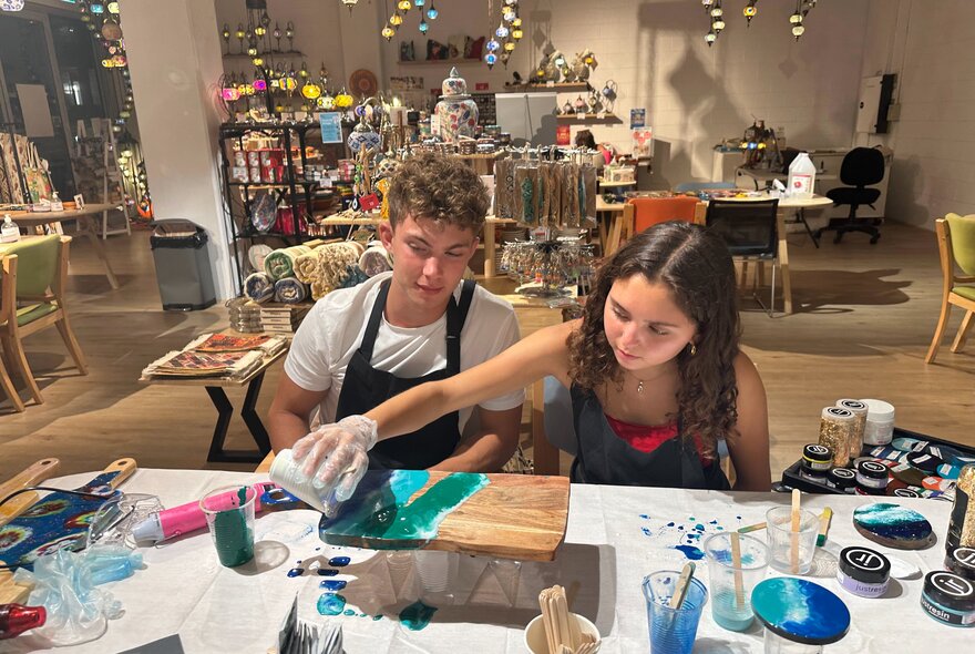 Children working on a resin art project at a worktable with art tools.