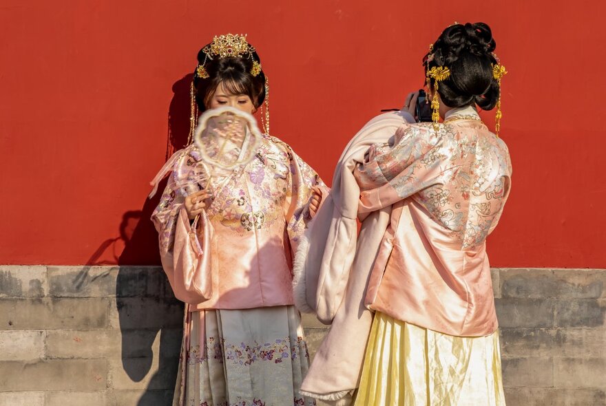 Performers wearing traditional Chinese outfits in embroidered satin and silk.