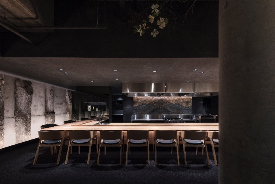 Japanese restaurant interior with central shared table and chairs around a central chef station.