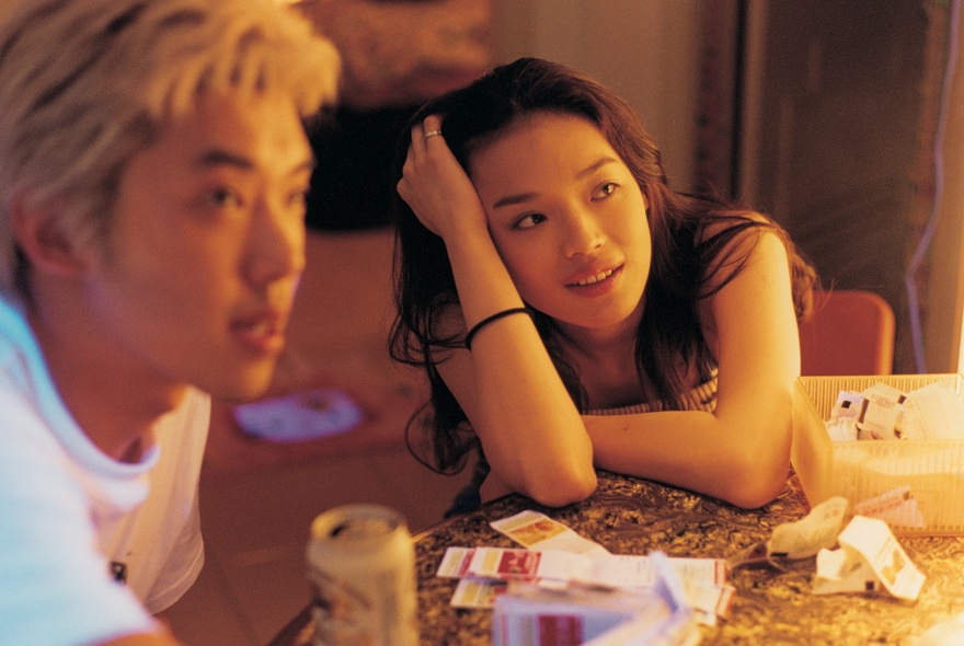 Movie still of a couple looking to their left from a table.
