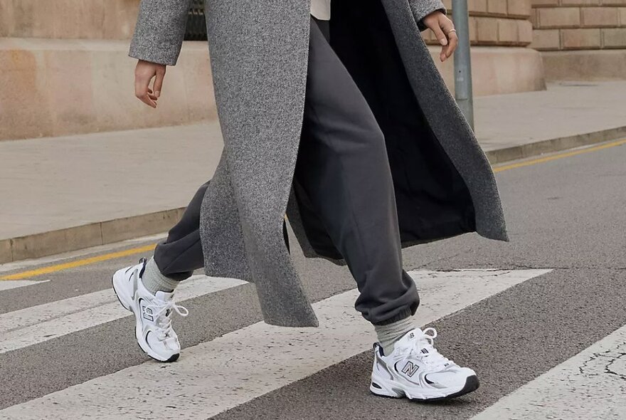 A woman wearing a pair of white retro new balance sneakers with an all grey outfit.