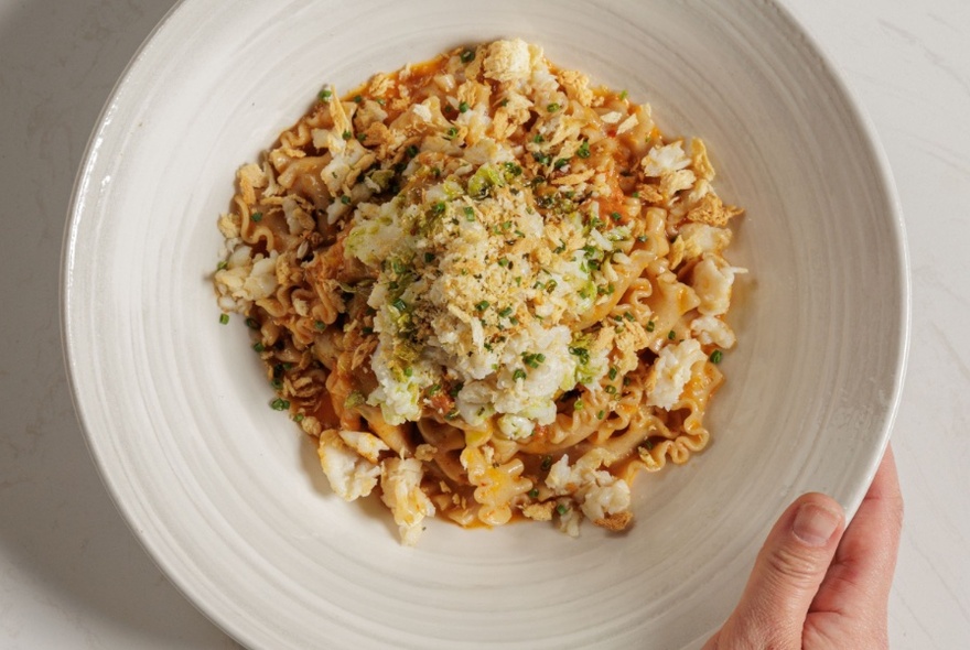 An Asian-inspired noodle dish presented in a white bowl.