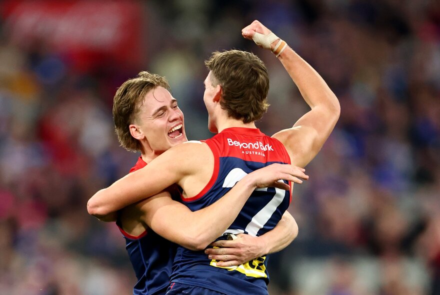 Melbourne football club players hug jubilantly during a game. 