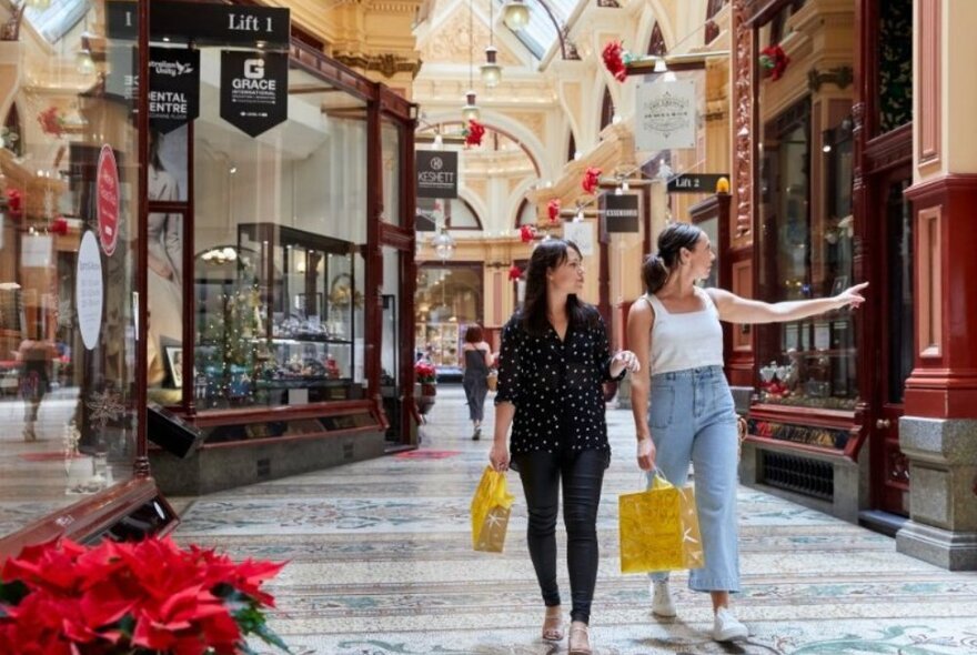 Two women walking through a shopping arcade.