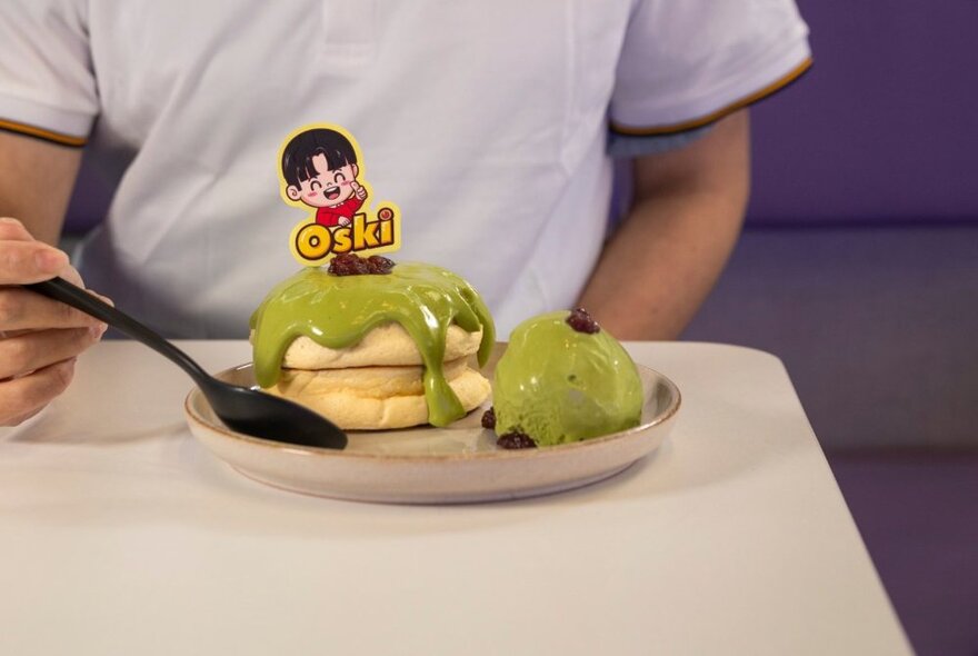 A cropped person about to eat a soufflé with matcha sauce. 