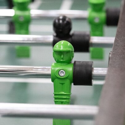 Close up of a foosball table with green and black players.
