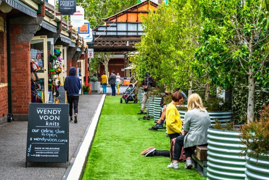 People sitting in a grassy area at Queen Victoria Market outside Wendy Voon Knits.