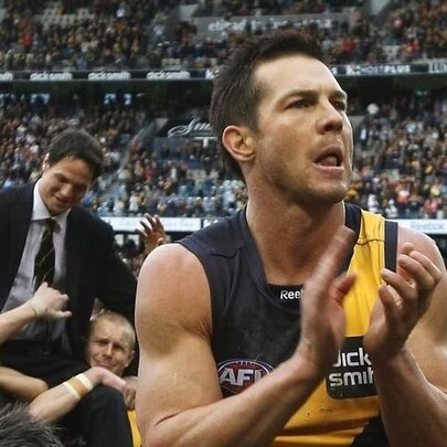 Former AFL star Ben Cousins clapping on the field in a packed stadium, while wearing the yellow and black jumper of the Richmond Football Club.