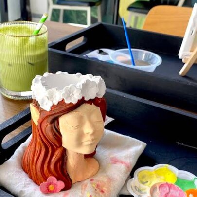 Matcha drink next to a clay sculpture with paints and palette.