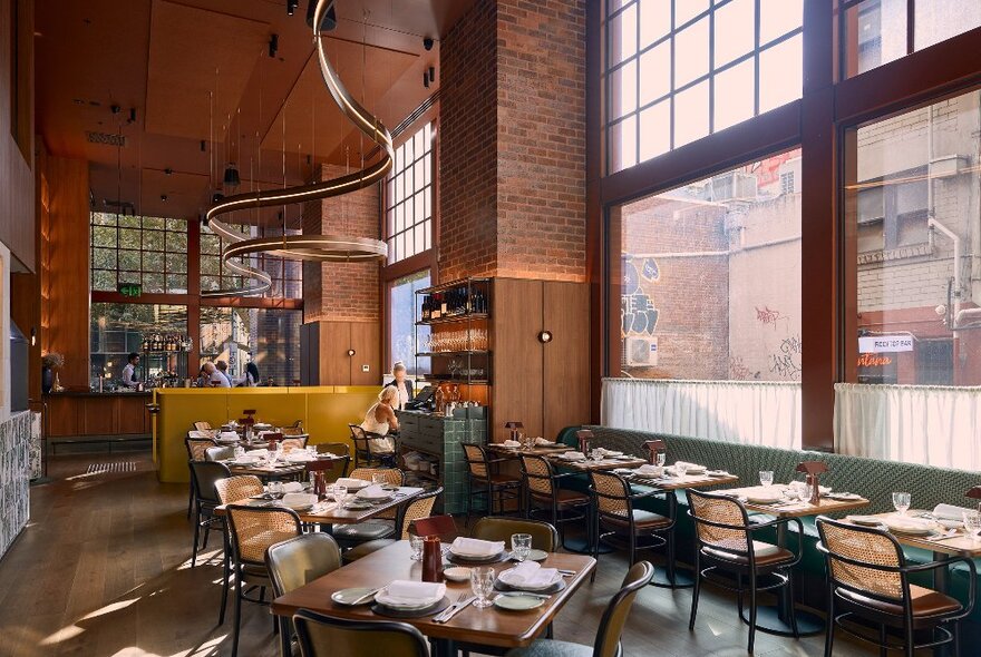 Inside a modern restaurant with a brick wall and a spiral light fixture hanging from the ceiling. 