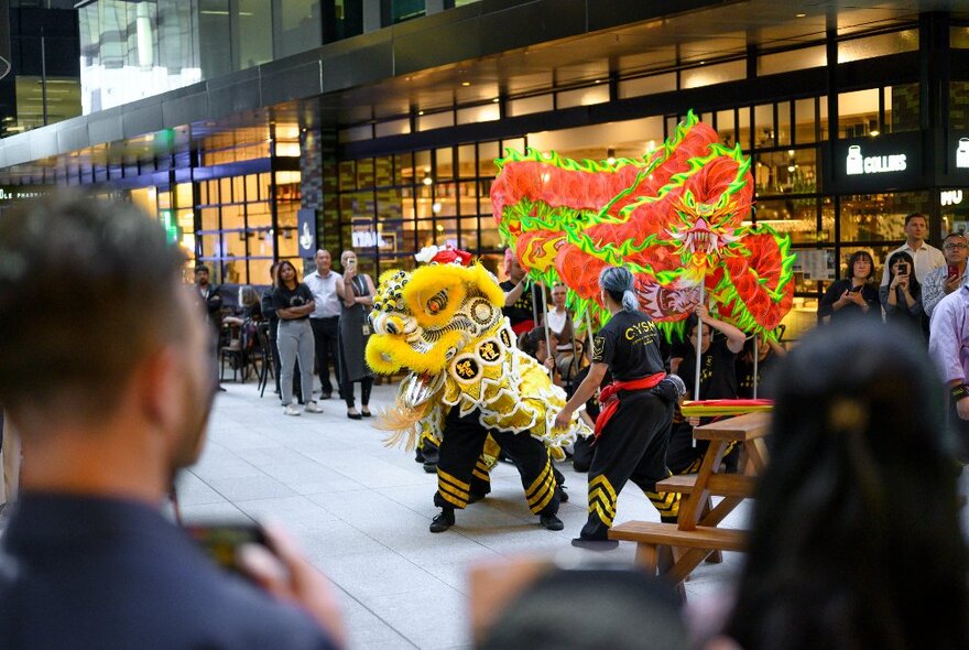 People at Collins Square outdoor plaza watching a lion dance performance as part of Lunar New Year celebrations.